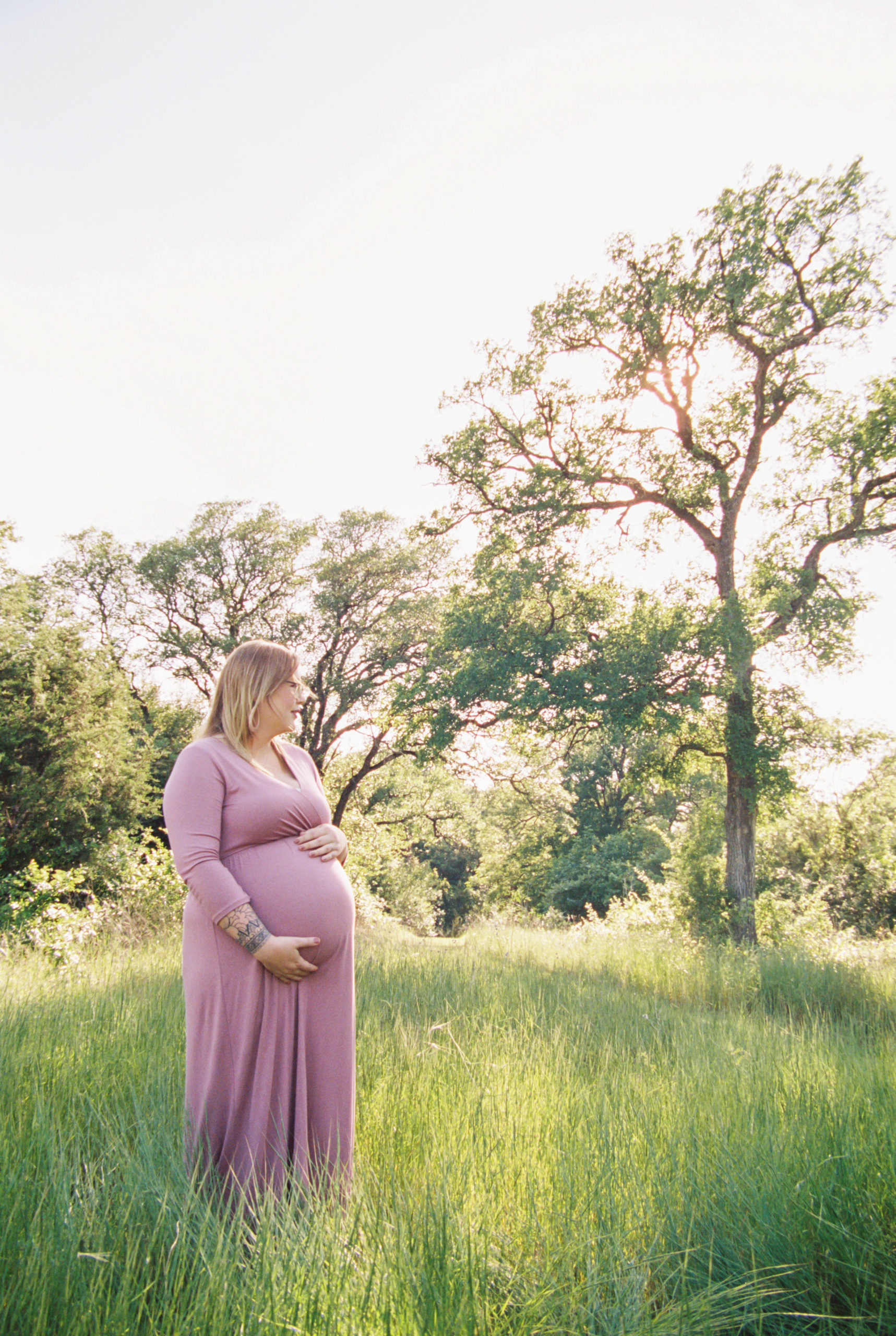 abby holds her belly looking to the right at the grass