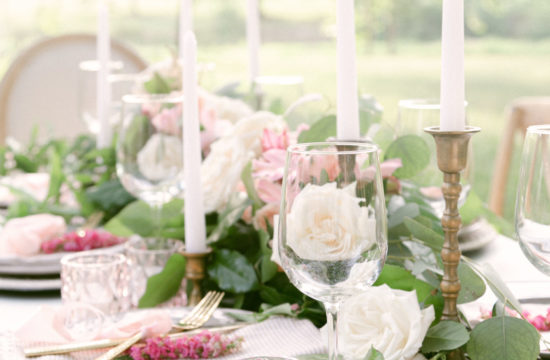 a close of of the outside table, the table is set with flowers and candle sticks