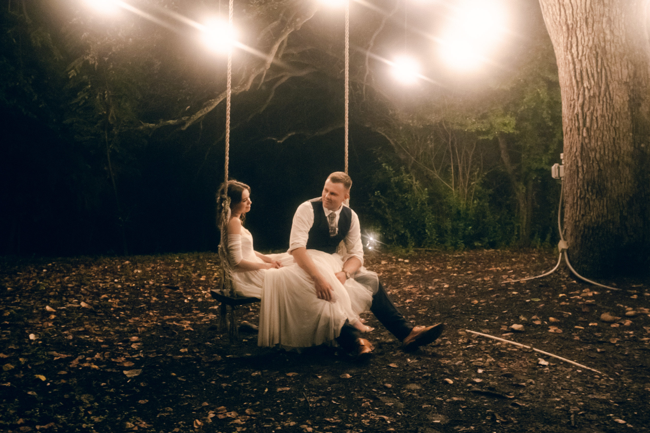 Elle and henry sit in a swing together at the end of their wedding at Mercury Hall. This image is on the contact page of the rae allen website.