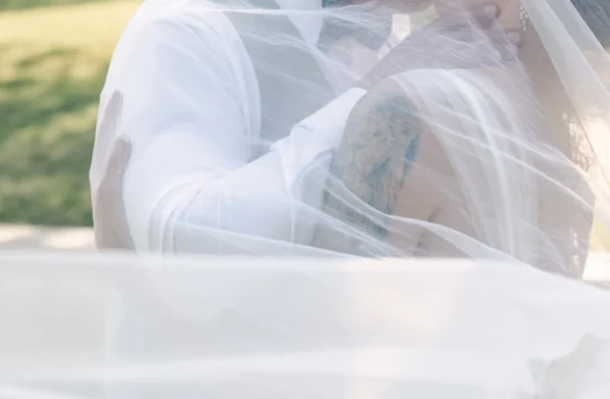 A color image of Saige and John kissing while a veil is . This is an image taken by Belton Photographer Rae Allen Photography
