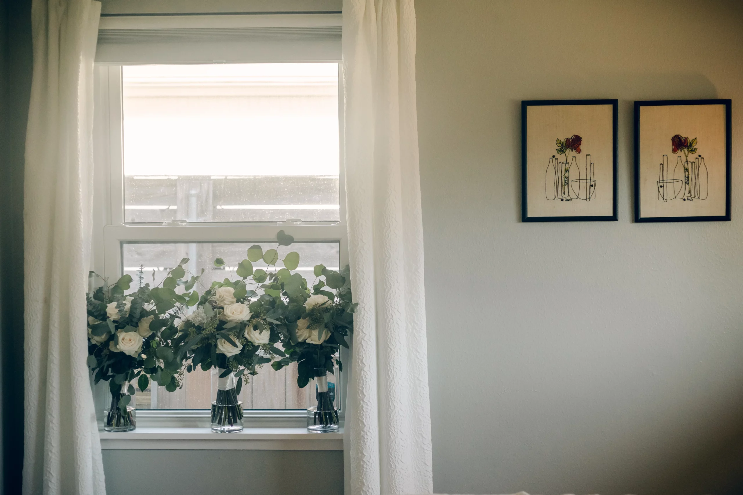 a detail image of three vases full of white and green bouquets sitting in a window