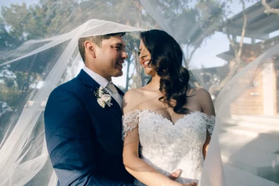 The bride and groom hold each under under the bridal veil for their just married portraits 