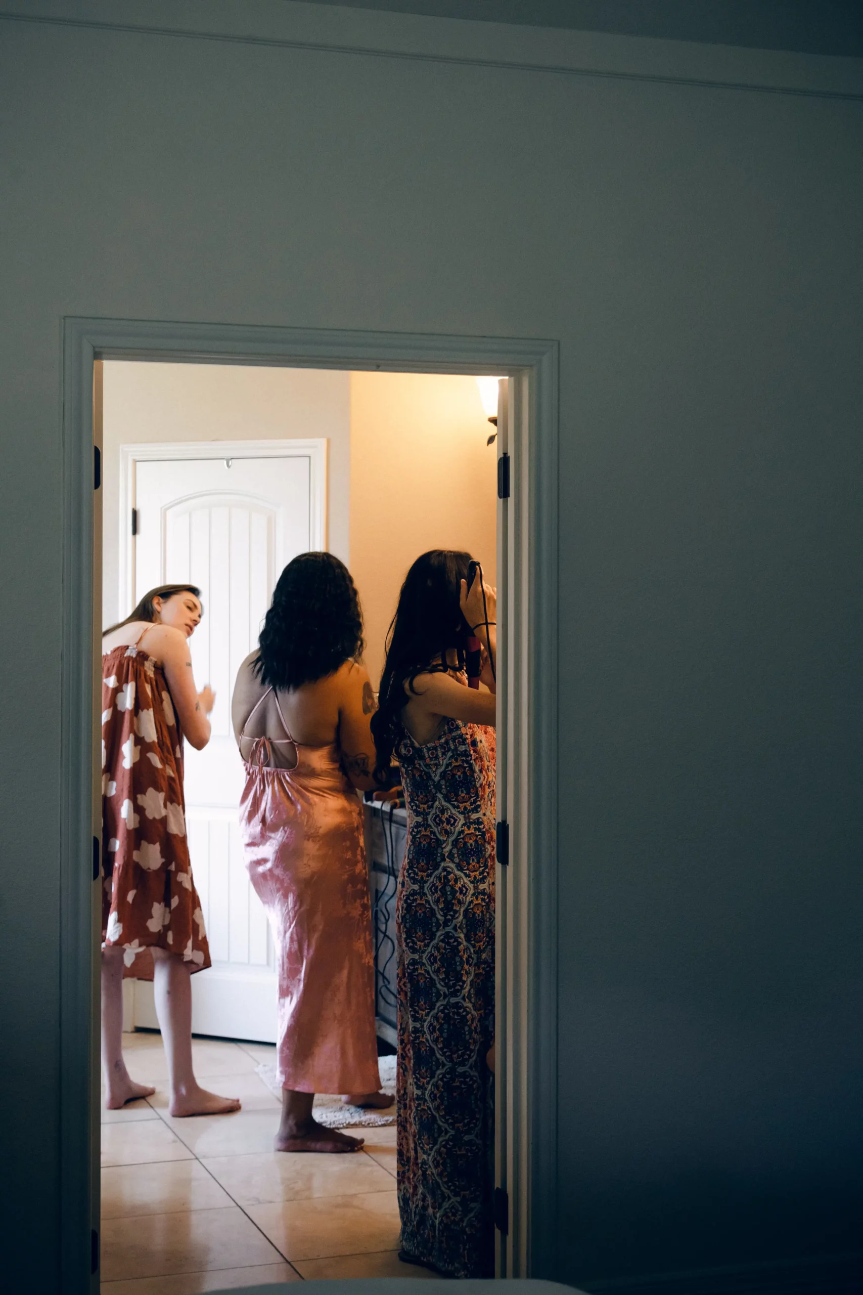 a shot through a door of the bride getting ready in the bathroom with her friends