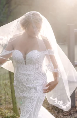 A bride looks down through her veil while walking in a field | the feature image of Rae Allen Photography's gallery a fall session at stonehaus