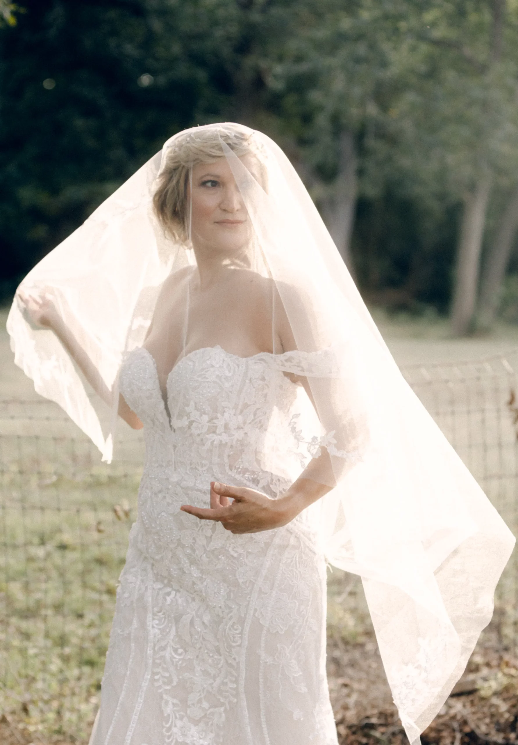 A close up of the bride with a veil draped over her in the middle of an open field during golden hour | Rae Allen Photography | Stonehaus Fall Styled Shoot