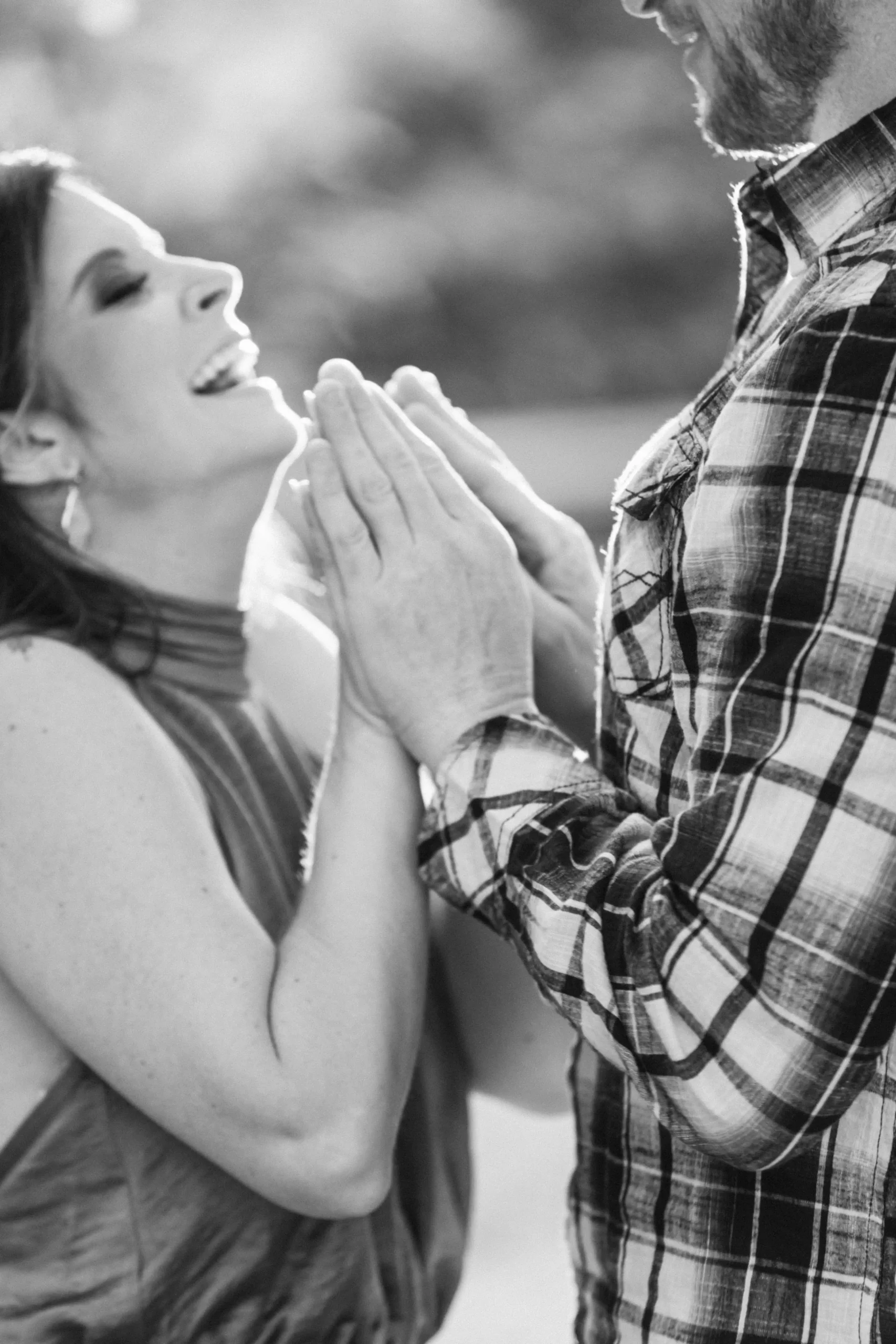 A black and white image of a couple placing their palms together during their engagement shoot at the arboretum in Waco