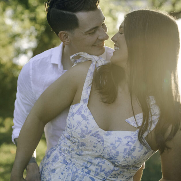 a couple smiles at each other while being backlit by the sun, the man is sticking out his tounge to the woman as she laughs | the engaged couple, Rae allen photography