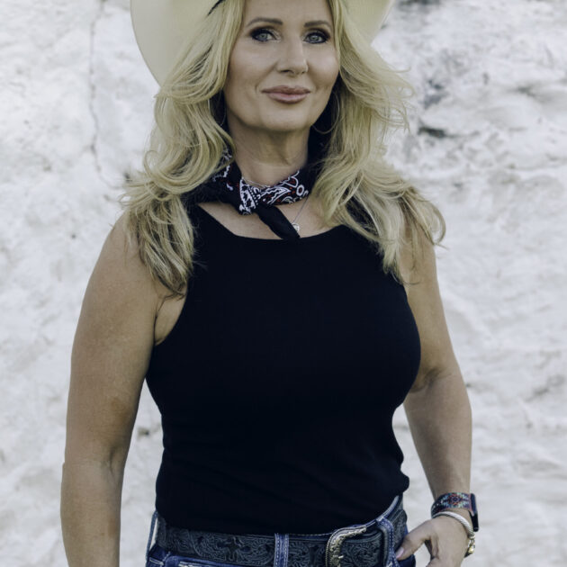 Head shot of refro realty agent Betty renfro. she is in a black top with a cowboy hat sitting on top of her blond hair, headshots, rae allen photography